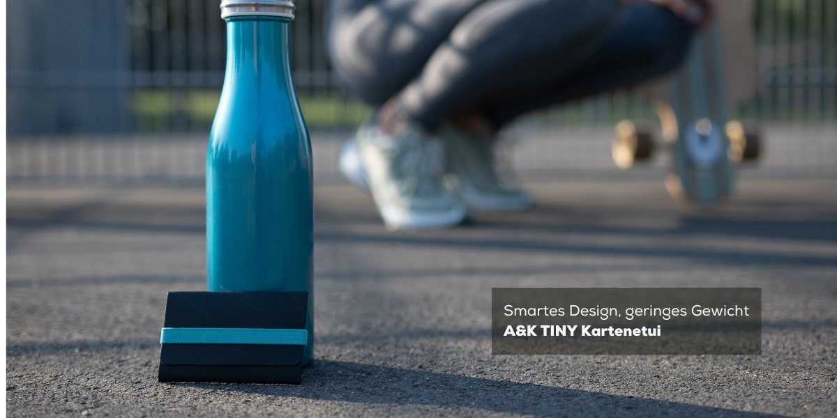 Kompaktes Design, lebendige Farben: A&K TINY Kartenetui in Schwarz/Mint, präsentiert neben einer Trinkflasche und einer skatenden Frau - der perfekte Begleiter für deinen urbanen Lifestyle.